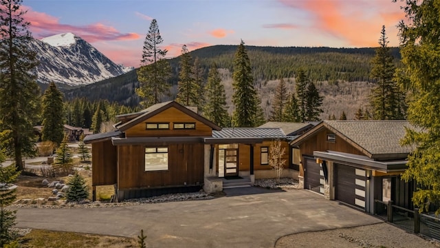427 Whispering Pines Cir, Blue River, CO 80424 - view of front of house featuring driveway, a mountain view, an attached garage, and a view of trees