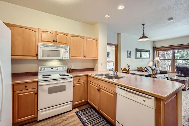 22714 US Highway 6 Unit 5945, Keystone, CO 80435 - kitchen featuring white appliances, a peninsula, open floor plan, light wood-style floors, and light brown cabinets