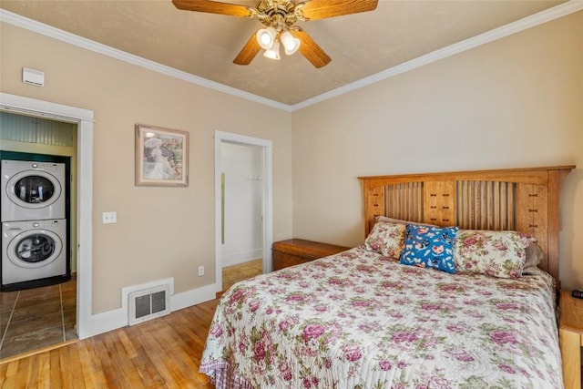 399 E Jefferson Ave, Hayden, CO 81639 - bedroom with estacked washer and dryer, ornamental molding, wood finished floors, baseboards, and ceiling fan