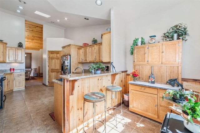 3692 County Road 7, Craig, CO 81625 - kitchen with stainless steel fridge, a peninsula, high vaulted ceiling, recessed lighting, and light stone countertops