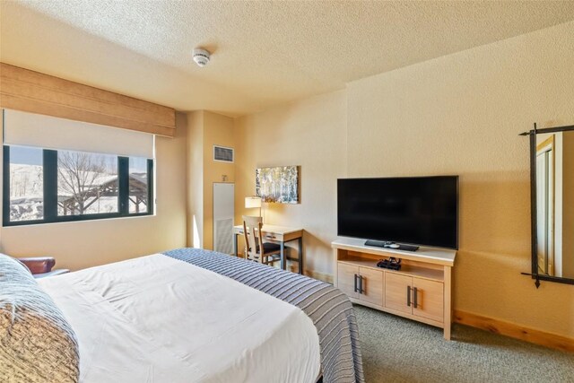 carpeted bedroom featuring baseboards, a textured ceiling, and visible vents