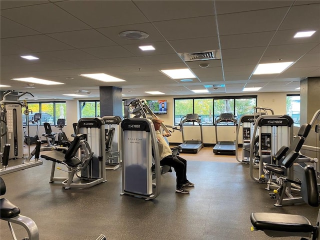 exercise room with a wealth of natural light, a drop ceiling, and visible vents