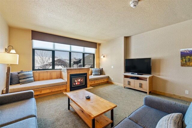 carpeted living room with baseboards, a glass covered fireplace, and a textured ceiling