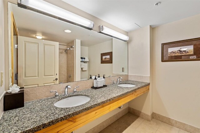 bathroom featuring baseboards, tile patterned floors, a sink, and a shower
