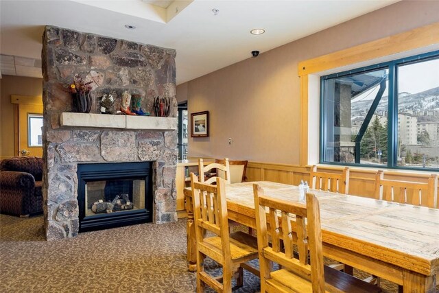 dining area with a fireplace, carpet, and wainscoting