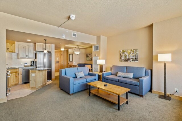 living room featuring a textured ceiling, visible vents, and light colored carpet