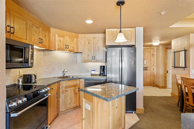 kitchen with appliances with stainless steel finishes, a sink, light brown cabinetry, and a textured ceiling
