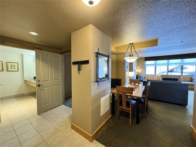 dining space featuring baseboards, light tile patterned flooring, and a textured ceiling