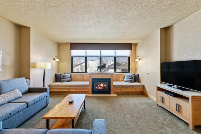 carpeted living room with a textured wall, a glass covered fireplace, and a textured ceiling