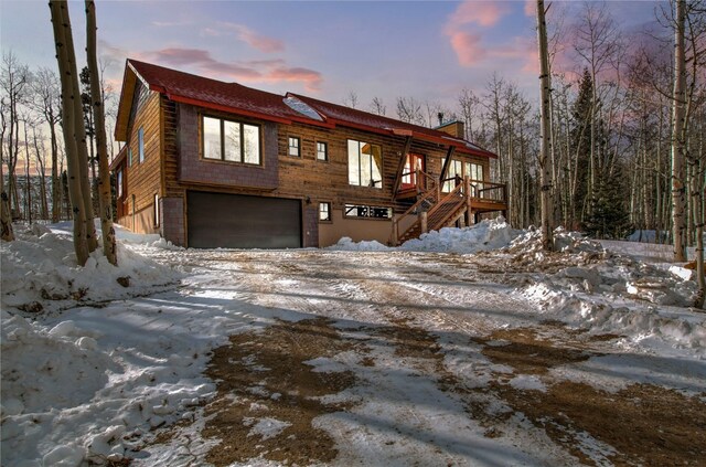 view of front of property with an attached garage, driveway, a chimney, and stairs