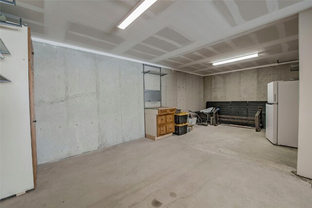 unfinished basement with freestanding refrigerator