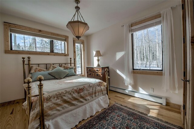 bedroom featuring a baseboard heating unit and light wood finished floors