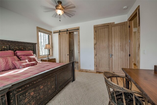 bedroom with a barn door, light wood finished floors, and a ceiling fan
