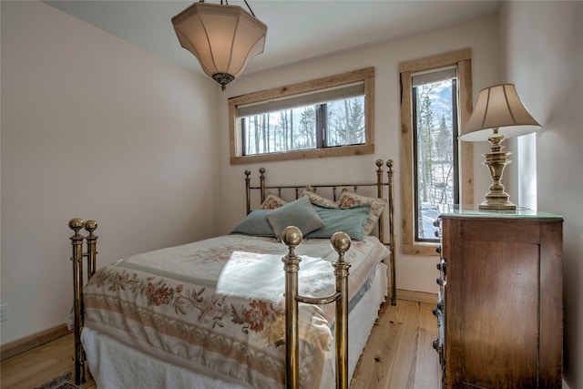 bedroom with baseboards, light wood-style floors, and multiple windows