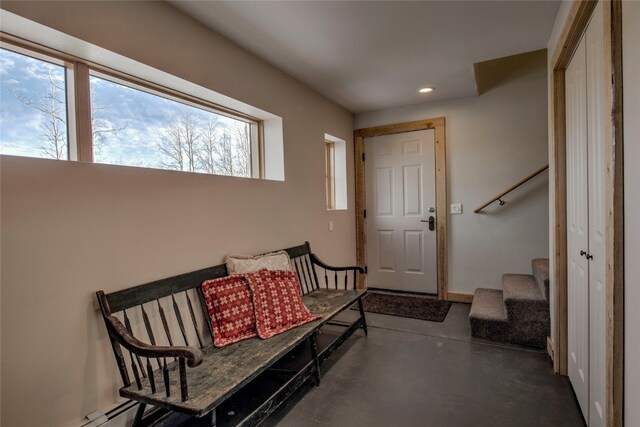 foyer featuring recessed lighting, stairway, finished concrete flooring, and baseboard heating