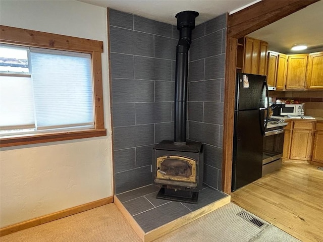 1325 Dream Island Plz Unit 55, Steamboat Springs, CO 80487 - detailed view of freestanding refrigerator, stainless steel gas stove, a wood stove, and white microwave