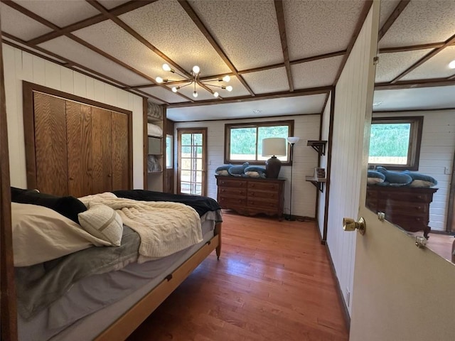 1325 Dream Island Plz Unit 55, Steamboat Springs, CO 80487 - bedroom with wooden walls, light wood-style flooring, multiple windows, and a chandelier