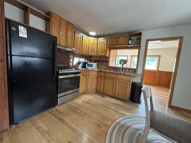 1325 Dream Island Plz Unit 55, Steamboat Springs, CO 80487 - kitchen with freestanding refrigerator, gas stove, under cabinet range hood, open shelves, and light wood finished floors