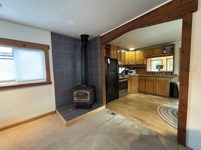 1325 Dream Island Plz Unit 55, Steamboat Springs, CO 80487 - kitchen with stainless steel gas stove, freestanding refrigerator, a wood stove, white microwave, and light carpet