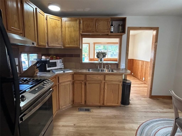 1325 Dream Island Plz Unit 55, Steamboat Springs, CO 80487 - kitchen featuring gas stove, under cabinet range hood, white microwave, light wood finished floors, and wood walls