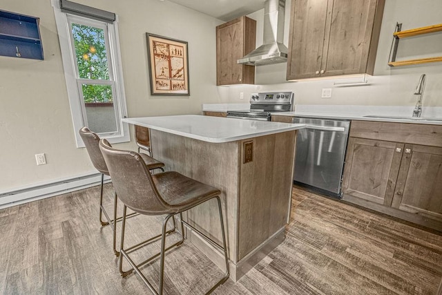 1800 Burgess Creek Rd SW Unit 209, Steamboat Springs, CO 80487 - kitchen featuring wall chimney exhaust hood, appliances with stainless steel finishes, a sink, a baseboard radiator, and wood finished floors