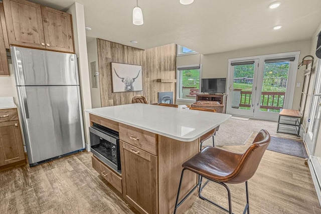 1800 Burgess Creek Rd SW Unit 209, Steamboat Springs, CO 80487 - kitchen with stainless steel appliances, light wood-style floors, open floor plan, a kitchen breakfast bar, and light countertops