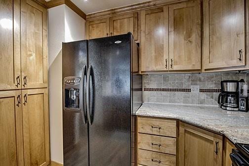 765 Columbine Rd Unit C103, Breckenridge, CO 80424 - kitchen with black fridge with ice dispenser, backsplash, light stone countertops, and brown cabinets