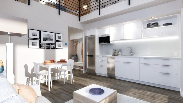 185 Lusher Ct Unit 203, Frisco, CO 80443 - kitchen featuring a towering ceiling, wood finished floors, white cabinetry, a sink, and stainless steel appliances