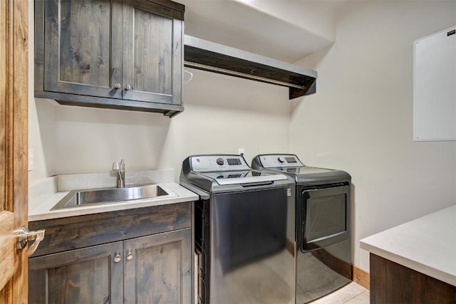 washroom featuring cabinet space, light tile patterned flooring, a sink, washer and dryer, and baseboards