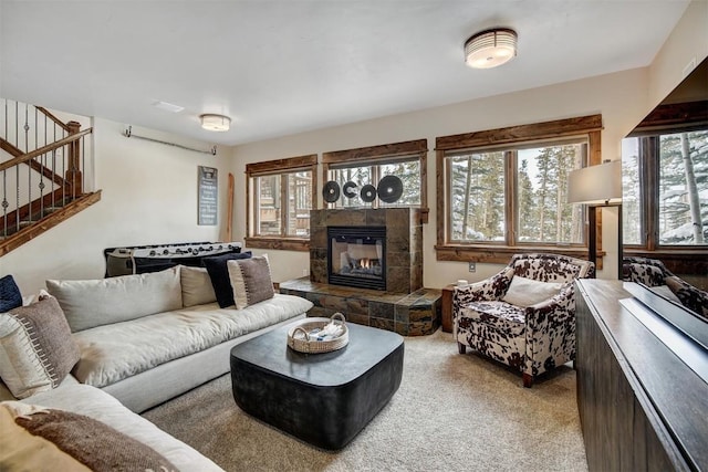 living room featuring carpet floors, stairway, and a tile fireplace