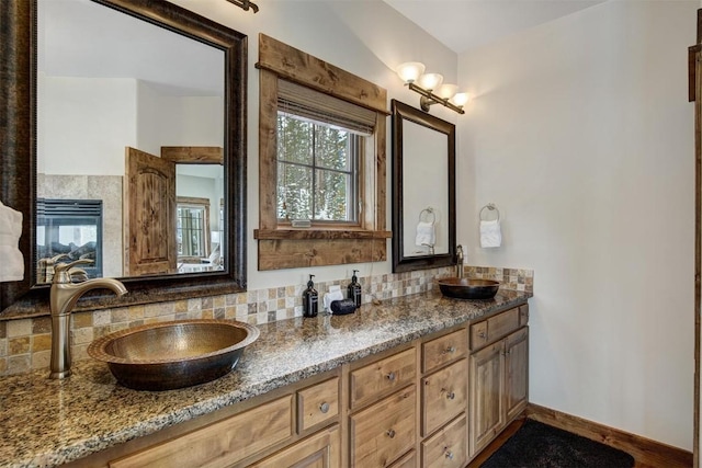 full bathroom with tasteful backsplash, a sink, baseboards, and double vanity