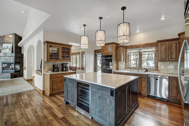 kitchen with wine cooler, stainless steel appliances, a sink, light countertops, and dark wood finished floors