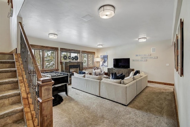 carpeted living area featuring stairs, baseboards, and a fireplace