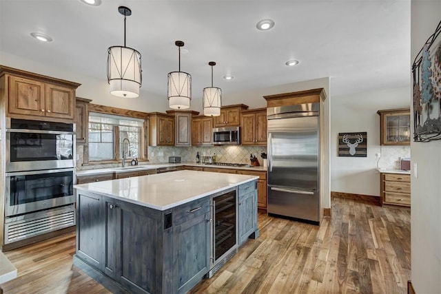 kitchen with stainless steel appliances, wine cooler, a sink, and wood finished floors