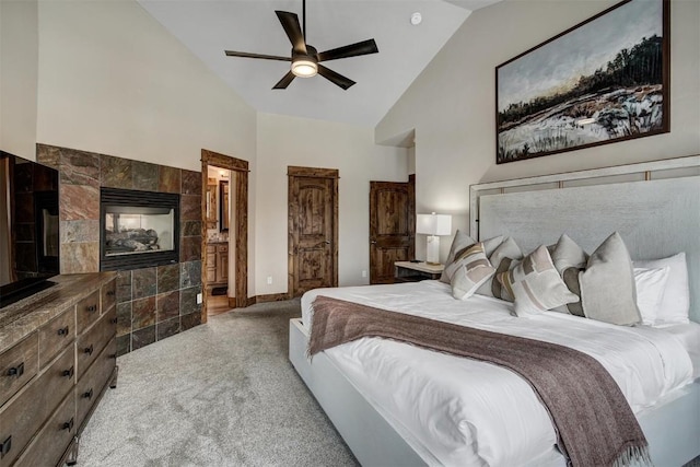 carpeted bedroom with connected bathroom, a fireplace, high vaulted ceiling, and a ceiling fan