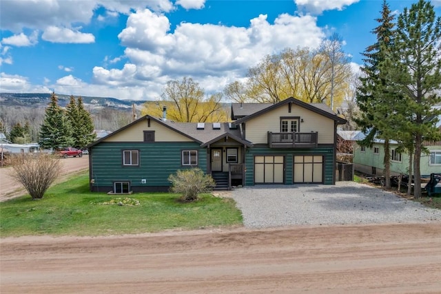 77 Lincoln St, Yampa, CO 80483 - view of front of house with gravel driveway, a front yard, an attached garage, a balcony, and a mountain view