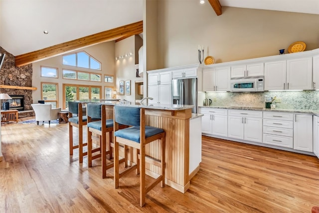 1118 Penstemon Rd, Dillon, CO 80435 - kitchen with high vaulted ceiling, stainless steel fridge, white microwave, beam ceiling, and a fireplace