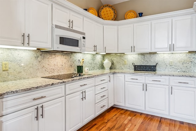 1118 Penstemon Rd, Dillon, CO 80435 - kitchen featuring white microwave, black electric stovetop, white cabinets, light wood-type flooring, and decorative backsplash