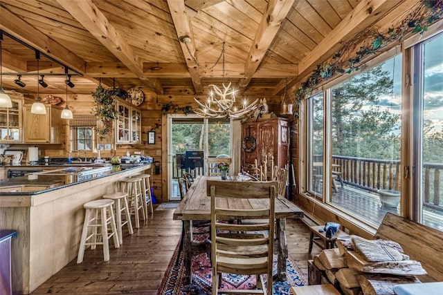 664 Tonkawa Rd, Hartsel, CO 80449 - dining space with a wood ceiling with exposed beams, dark wood-style flooring, wood walls, healthy amount of natural light, and a chandelier