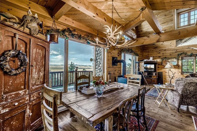 664 Tonkawa Rd, Hartsel, CO 80449 - dining space with wood-type flooring, wood walls, a chandelier, a wood ceiling with exposed beams, and a wood stove