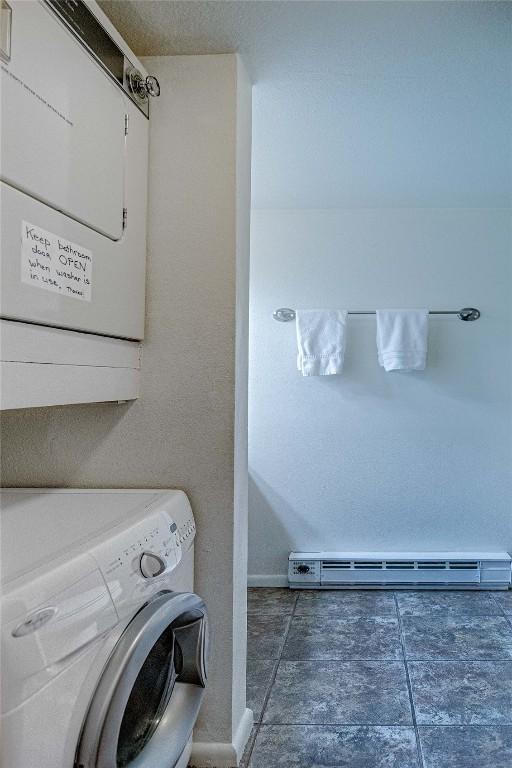 laundry area featuring stacked washer / dryer and a baseboard radiator