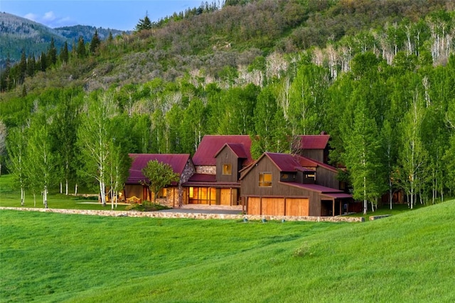 33225 Painted Pony Ln, Steamboat Springs, CO 80487 - rear view of property featuring a lawn, a mountain view, a wooded view, and stone siding