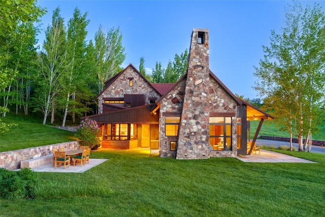 33225 Painted Pony Ln, Steamboat Springs, CO 80487 - back of property featuring stone siding, a standing seam roof, a lawn, a patio area, and a chimney