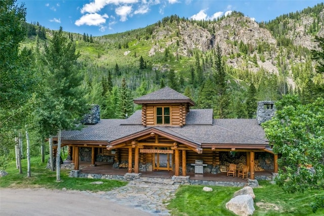 33225 Painted Pony Ln, Steamboat Springs, CO 80487 - view of front of house featuring log siding, a forest view, a mountain view, and a chimney