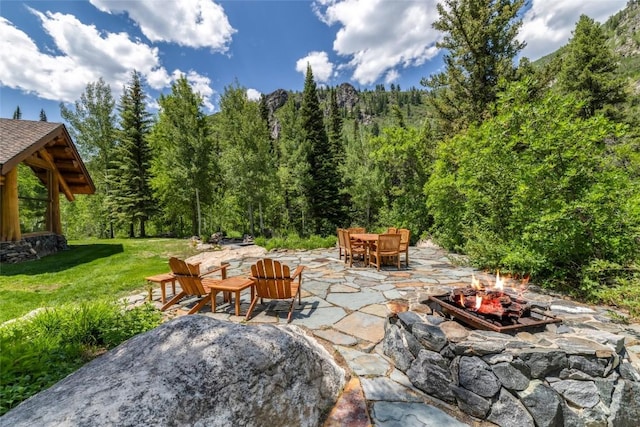 33225 Painted Pony Ln, Steamboat Springs, CO 80487 - view of patio / terrace featuring an outdoor fire pit, outdoor dining area, and a wooded view