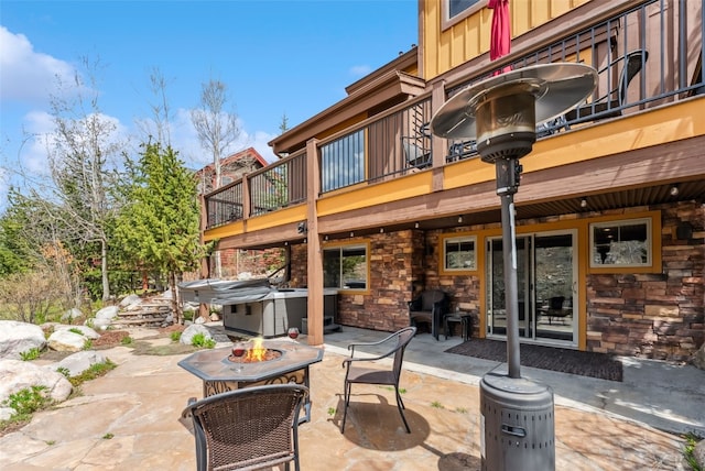200 Rachel Ln, Breckenridge, CO 80424 - back of house with an outdoor fire pit, a hot tub, a patio, a balcony, and stone siding