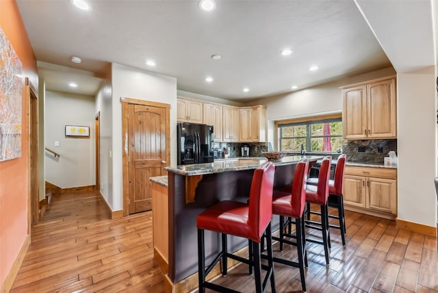 200 Rachel Ln, Breckenridge, CO 80424 - kitchen with black fridge, light wood finished floors, decorative backsplash, a kitchen bar, and recessed lighting