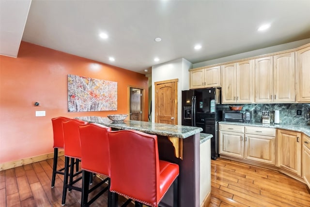 200 Rachel Ln, Breckenridge, CO 80424 - kitchen featuring light brown cabinets, a center island, black appliances, light wood-style floors, and a breakfast bar