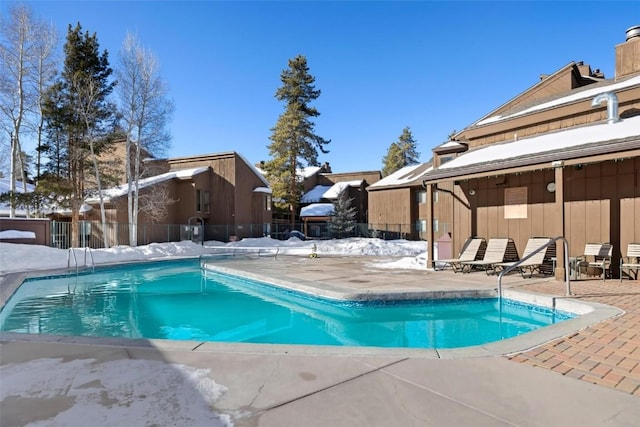 snow covered pool featuring fence, a patio area, and a fenced in pool