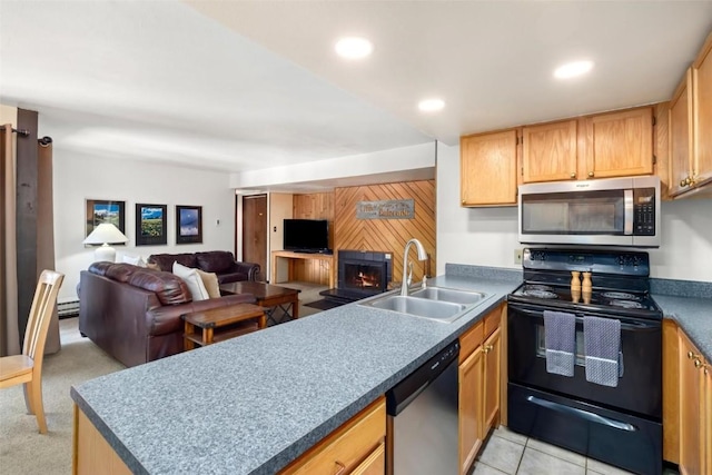 kitchen with a peninsula, a sink, open floor plan, appliances with stainless steel finishes, and a lit fireplace